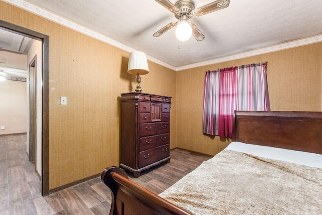 bedroom featuring ceiling fan, wood finished floors, and wallpapered walls