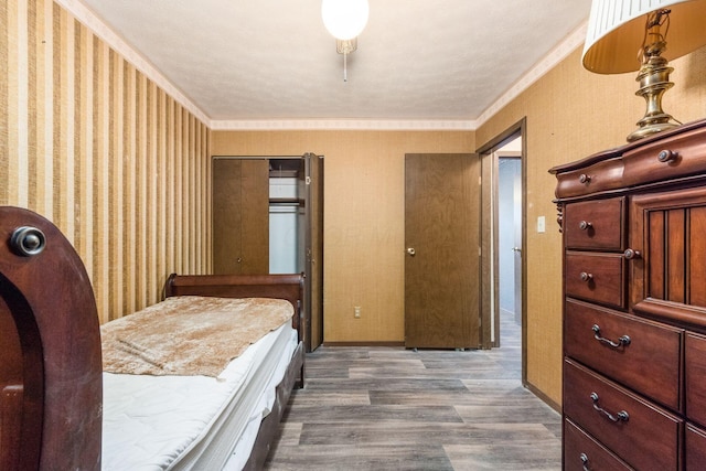 bedroom with baseboards, ornamental molding, wood finished floors, and wallpapered walls