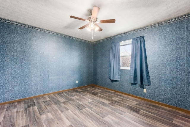 empty room featuring a ceiling fan, baseboards, and wood finished floors