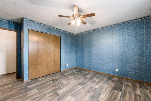 unfurnished bedroom featuring baseboards, ceiling fan, wood finished floors, a textured ceiling, and a closet