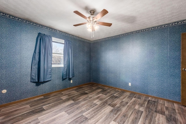 unfurnished room featuring wallpapered walls, ceiling fan, baseboards, and wood finished floors