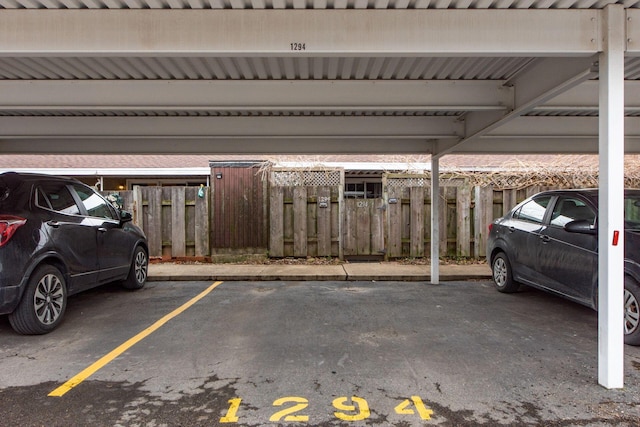 covered parking lot featuring fence