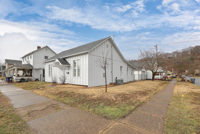 view of property exterior with roof with shingles, a yard, and board and batten siding