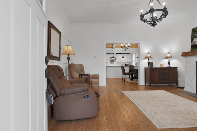 living room with a chandelier, a tile fireplace, and wood finished floors