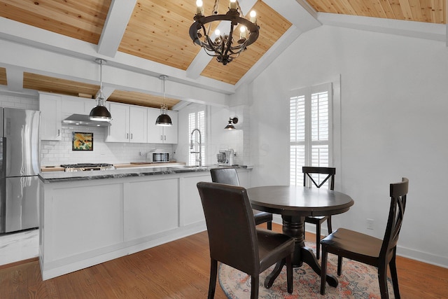 dining area featuring light wood-type flooring, wooden ceiling, vaulted ceiling with beams, and a notable chandelier