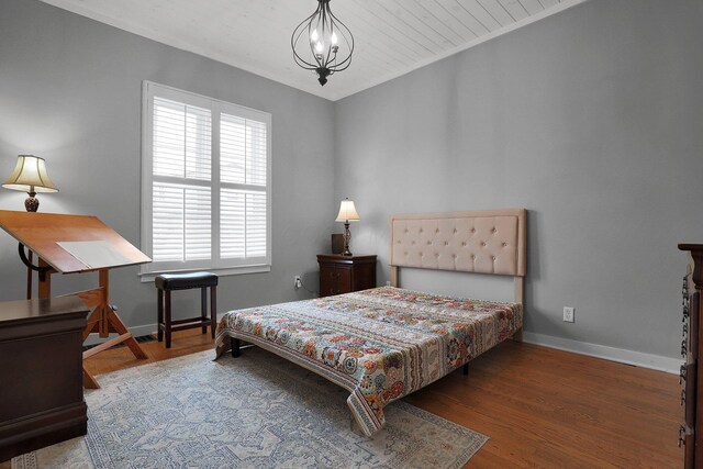 bedroom with baseboards, a chandelier, and wood finished floors