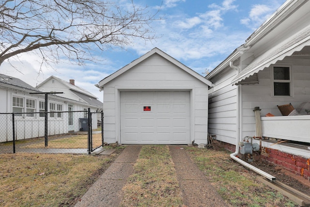 detached garage with a gate, driveway, and fence