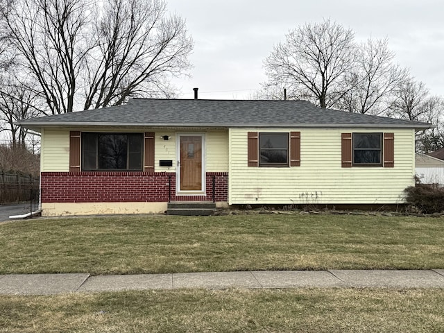 view of front facade featuring brick siding, a shingled roof, and a front lawn