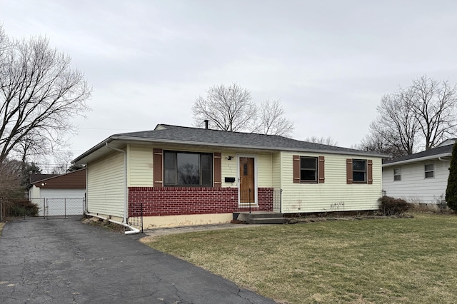 view of front of house with an outbuilding, brick siding, a front lawn, and fence