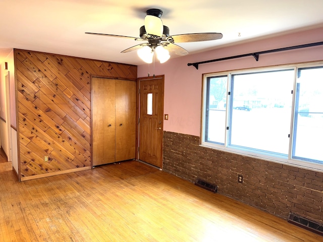 interior space with a wealth of natural light, visible vents, ceiling fan, and light wood finished floors