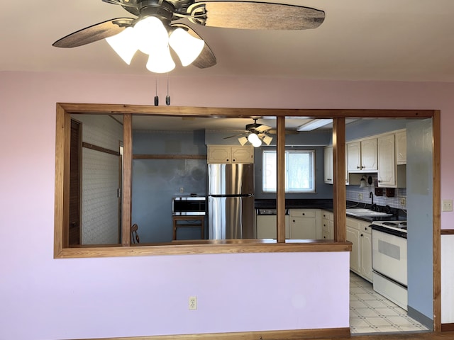 kitchen with white electric range oven, a ceiling fan, freestanding refrigerator, a sink, and dark countertops