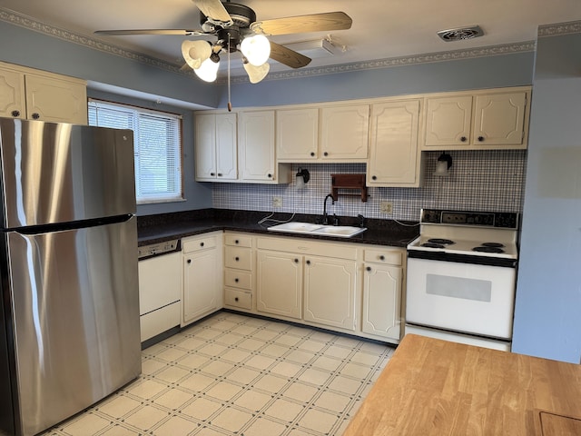 kitchen with white appliances, a ceiling fan, light floors, a sink, and dark countertops