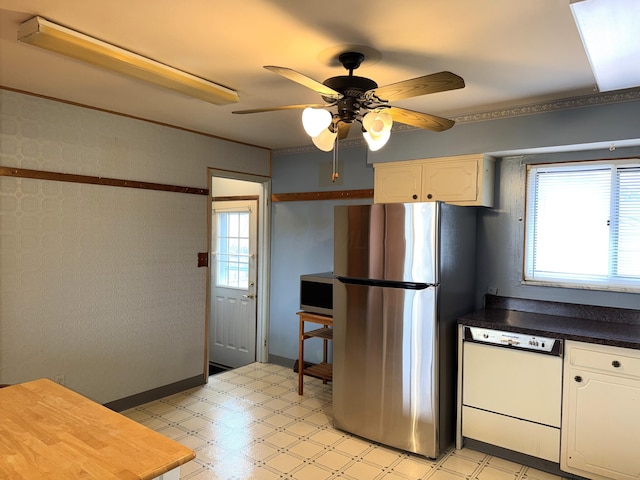 kitchen with stainless steel appliances, light floors, dark countertops, and a ceiling fan