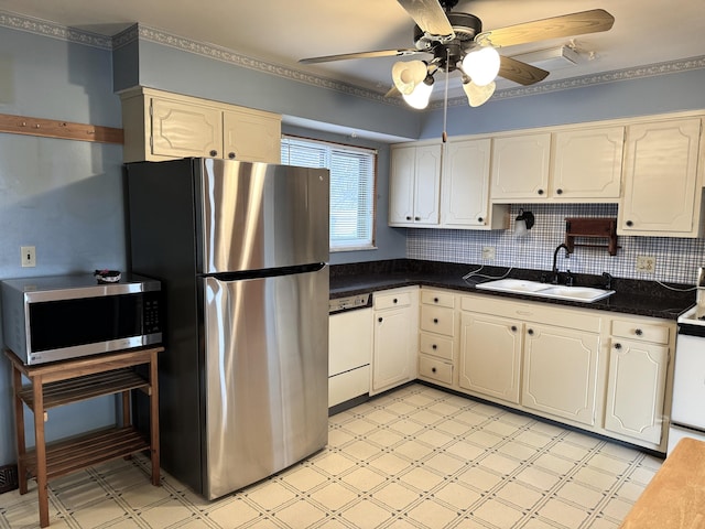 kitchen with a sink, dark countertops, stainless steel appliances, light floors, and ceiling fan