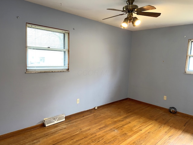 unfurnished room with hardwood / wood-style floors, plenty of natural light, visible vents, and ceiling fan