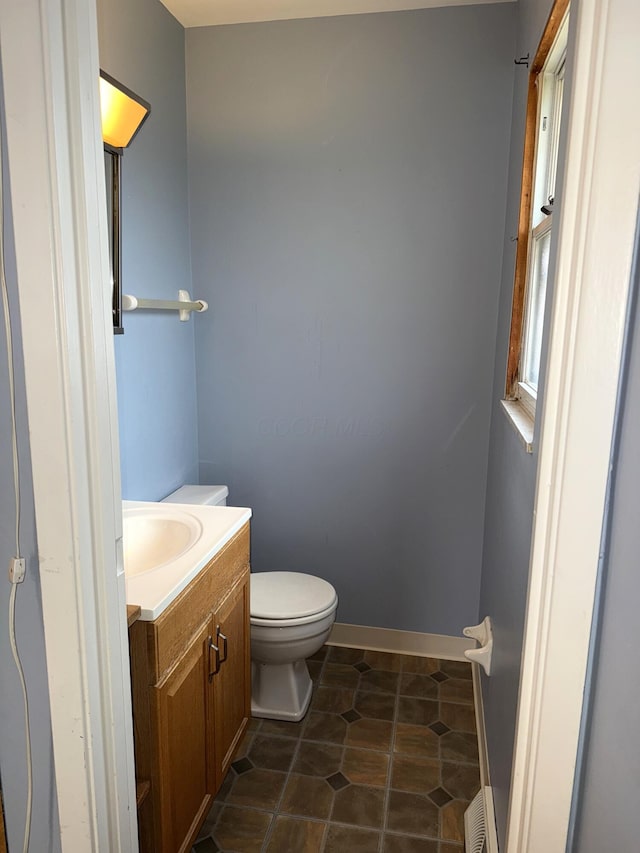 half bathroom with vanity, visible vents, baseboards, tile patterned floors, and toilet