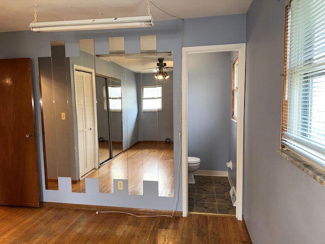 interior space featuring baseboards, toilet, wood finished floors, and a ceiling fan