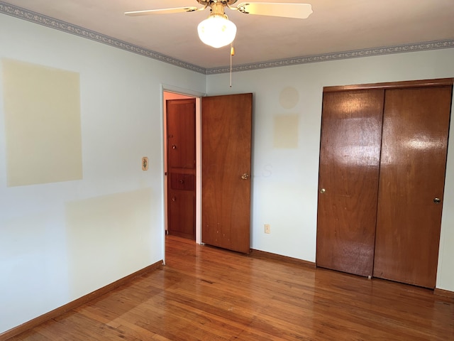 unfurnished bedroom with ceiling fan, a closet, baseboards, and wood finished floors