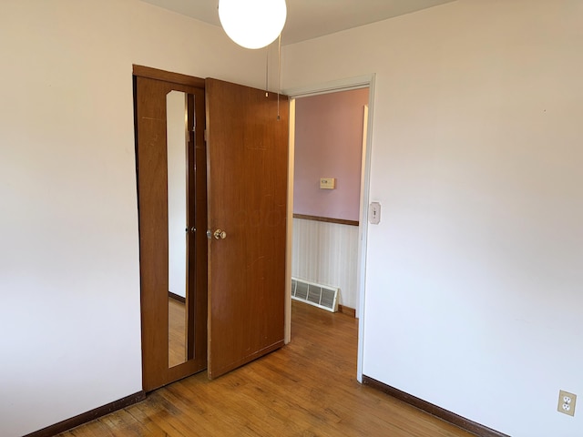 empty room featuring wood finished floors, visible vents, and baseboards