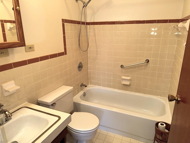 bathroom featuring bathing tub / shower combination, tile patterned flooring, wainscoting, tile walls, and toilet