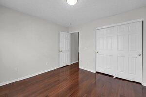 unfurnished bedroom featuring wood finished floors, baseboards, and a closet