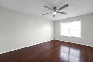 spare room featuring baseboards, wood finished floors, and ceiling fan