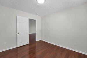 unfurnished room with a textured ceiling, baseboards, and wood finished floors