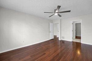 empty room with baseboards, wood finished floors, and a ceiling fan