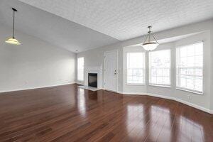 unfurnished living room featuring a fireplace, vaulted ceiling, wood finished floors, and baseboards