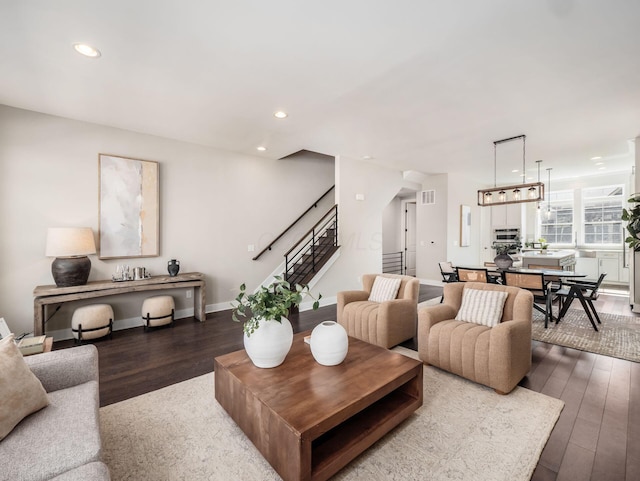 living area featuring recessed lighting, visible vents, dark wood-type flooring, and stairway