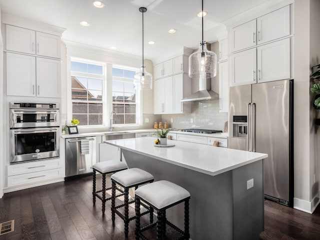 kitchen featuring a kitchen island, decorative backsplash, appliances with stainless steel finishes, white cabinetry, and a kitchen breakfast bar