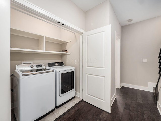 laundry area with laundry area, washing machine and dryer, baseboards, and wood finished floors