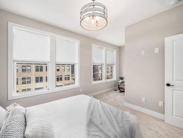 carpeted bedroom with baseboards and an inviting chandelier