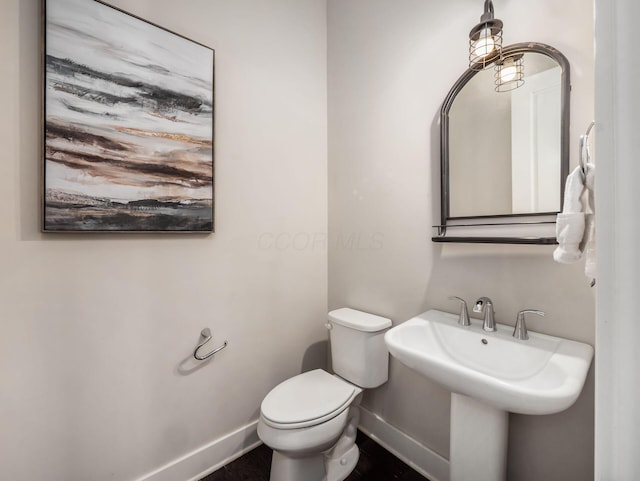 half bathroom featuring baseboards and toilet