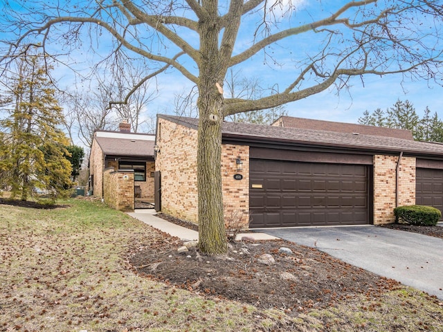 view of front of house with driveway, a chimney, an attached garage, a front lawn, and brick siding