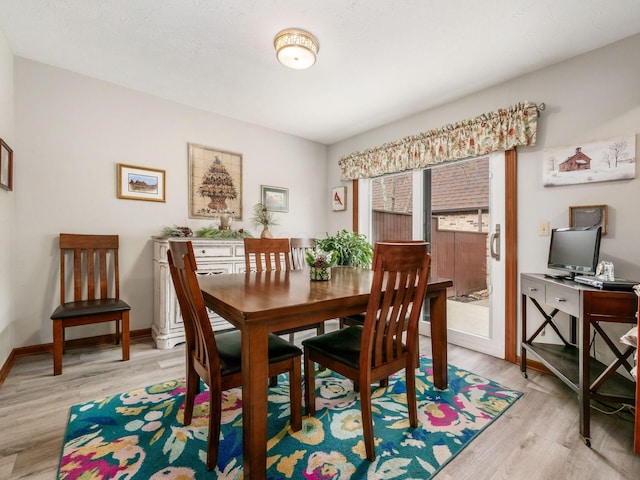 dining space featuring light wood finished floors and baseboards