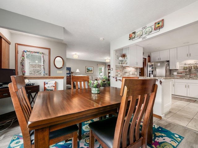 dining area featuring light wood-style floors and a textured ceiling