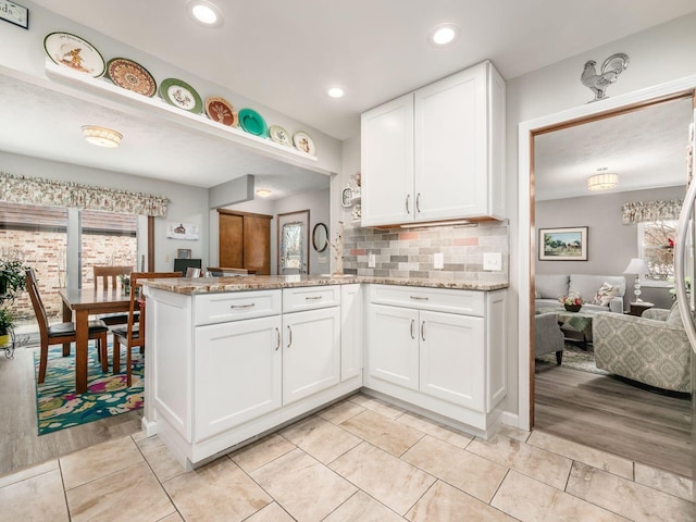 kitchen with a peninsula, backsplash, a wealth of natural light, and white cabinets