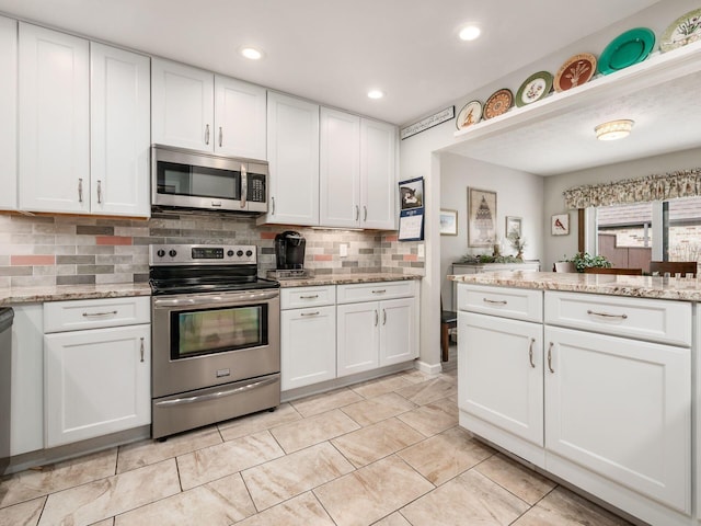 kitchen with appliances with stainless steel finishes, white cabinetry, and tasteful backsplash