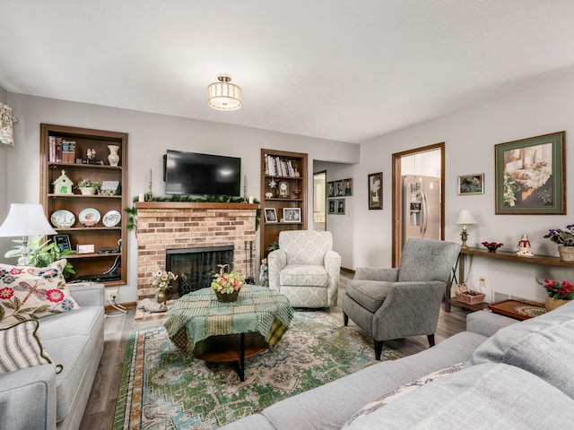 living room with a fireplace, wood finished floors, and built in features