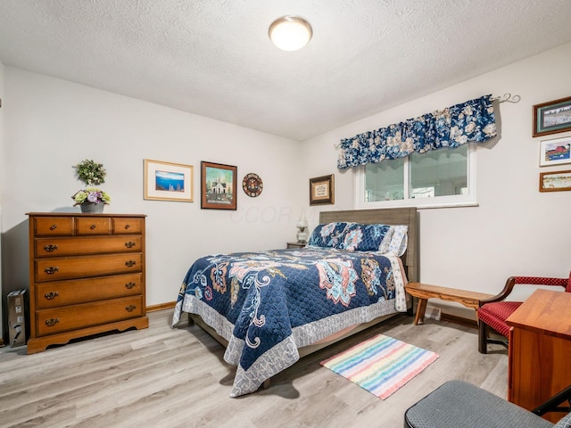 bedroom featuring a textured ceiling, baseboards, and wood finished floors