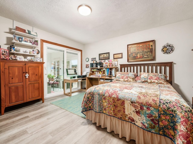 bedroom featuring access to exterior, light wood-style flooring, and a textured ceiling