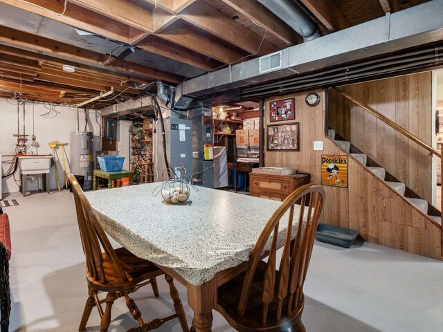 dining area with visible vents, stairway, finished concrete floors, electric water heater, and wooden walls