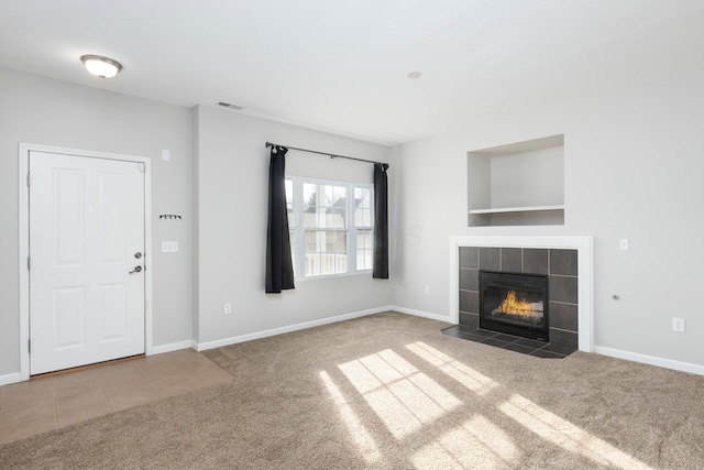 unfurnished living room with visible vents, a tile fireplace, baseboards, and carpet floors