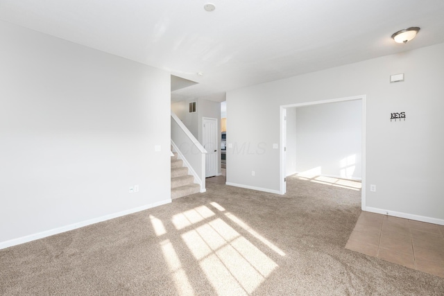 unfurnished living room featuring visible vents, carpet, tile patterned flooring, baseboards, and stairs