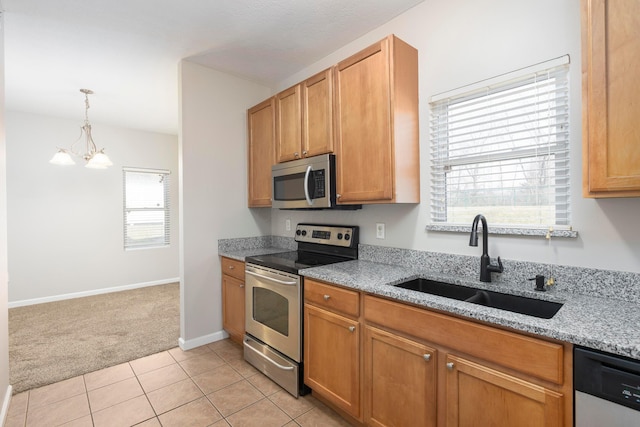 kitchen featuring light tile patterned floors, light stone countertops, a sink, appliances with stainless steel finishes, and light carpet