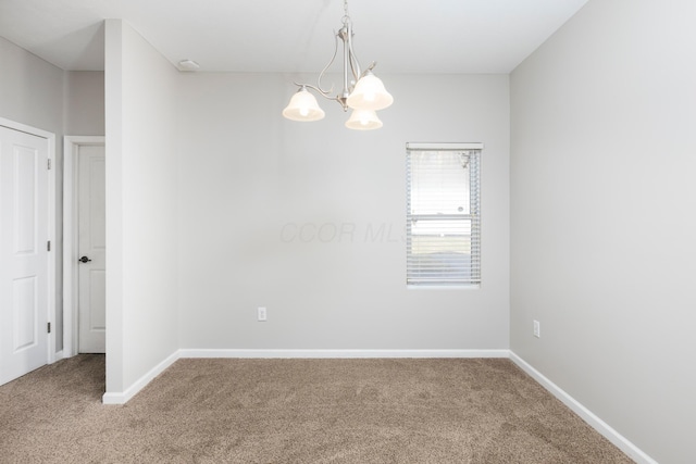 carpeted spare room with an inviting chandelier and baseboards