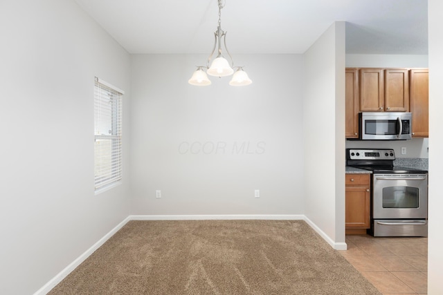 kitchen with brown cabinetry, baseboards, a chandelier, and stainless steel appliances