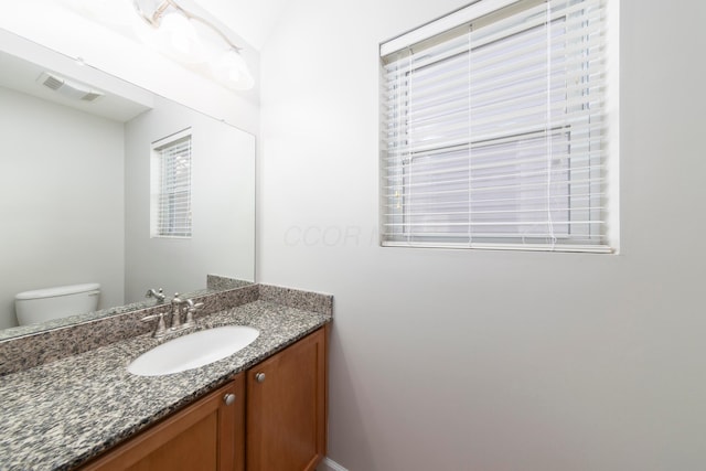 half bathroom featuring visible vents, toilet, and vanity