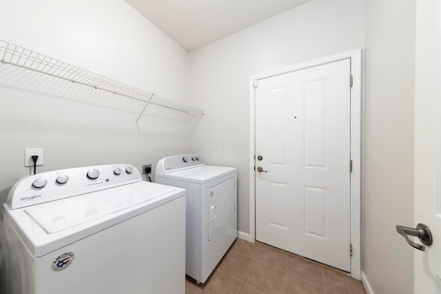 laundry room with light tile patterned floors, baseboards, laundry area, and washing machine and clothes dryer